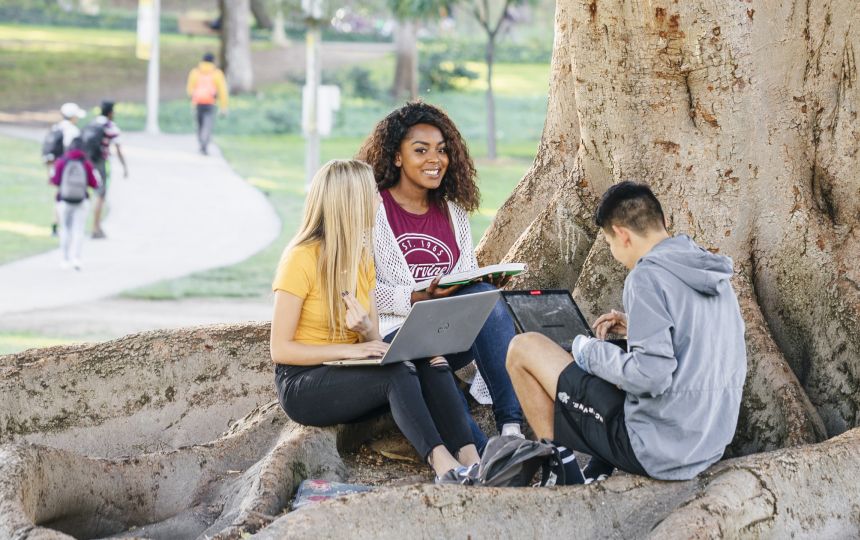 UCI students sitting by a tree